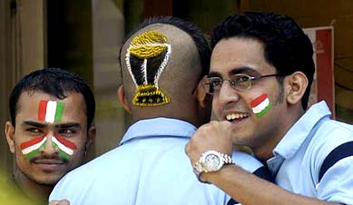 A cricket fan (C) sports a haircut in the shape of the World Cup as his friends wear the Tricolour on their faces in Mumbai 