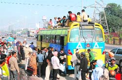 Passengers rush to board a private bus as Punjab Roadways buses stayed off roads in Jalandhar on Wednesday. 